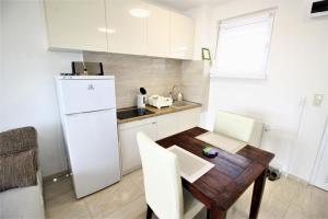 cocina con mesa de madera y nevera blanca en Rest House Apartman, en Nyíregyháza