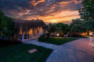 een huis met een grasdak met een zonsondergang op de achtergrond bij Naturelife Bungalows & SPA in Cıralı