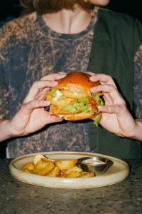 una mujer sosteniendo un sándwich delante de un plato de comida en Globe Runner Hostel, en Kiev