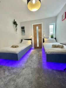 duas camas num quarto com luzes roxas em Cloud9 Guest House - by Coastline Retreats - Newly Renovated, Beautiful Ensuite Rooms Near Seafront in Town Centre, Netflix, SuperFast WiFi, Communal Kitchen em Bournemouth