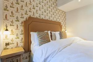 a bedroom with a bed with white sheets and wallpaper at The Inn West End in Woking