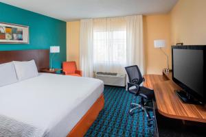 Habitación de hotel con cama y escritorio con TV. en Fairfield Inn & Suites Chicago Tinley Park, en Tinley Park