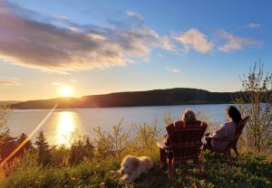 コーナーブルックにあるCoastal Lookout Suitesの椅子に座って2人、夕日を見ながら犬