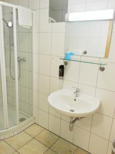 ein weißes Bad mit einem Waschbecken und einer Dusche in der Unterkunft Pension Weisses Lamm in Melk