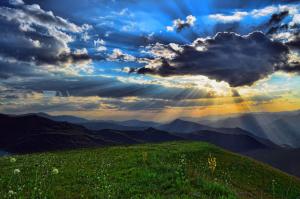 a green hill with the sun breaking through the clouds at Park Hotel Panorama in Bansko