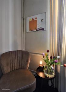 - un salon avec une chaise et une table fleurie dans l'établissement city Apartment "Op de Thermen", à Maastricht