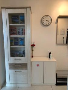 a white cabinet next to a wall with a clock at Ferienwohnung in Bern in Bern