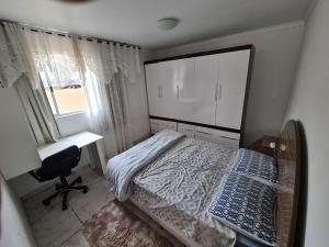 a bedroom with a bed and a desk and a window at Hostel AJBJ Turismo in Curitiba