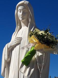 une statue d'une femme tenant un bouquet de fleurs dans l'établissement Apartments Kruno, à Međugorje