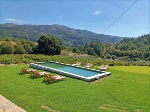 una piscina con sillas en un campo de césped en Quinta do Outeiro 1598, en Ponte da Barca