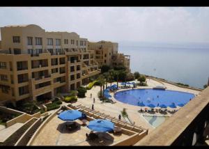 サワイマにあるDead Sea view Elite apartment Samara Resort traveler award 2024の青い傘と建物のあるプールの景色を望めます。