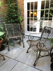 2 bancs assis sur un patio devant une porte dans l'établissement Kings Cross, self-contained house & private garden, à Londres