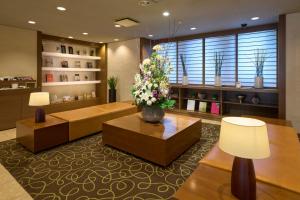 sala de estar con sofá y mesa con flores en Hotel Resol Machida, en Machida