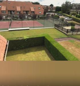 uitzicht op een tennisbaan met een gazon bij Picsine, Tennis résidence sévigné 300m mer in Deauville