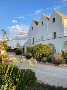 Un bâtiment blanc avec des fleurs devant lui dans l'établissement Masseria Grofoleo, à Locorotondo