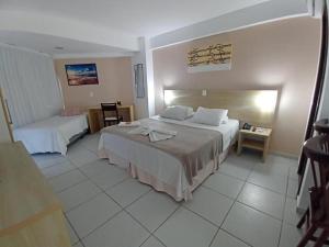 a hotel room with two beds and a table at Marsallis Praia JR 408 in Natal