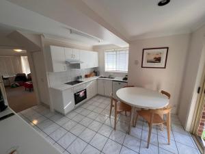 eine Küche mit einem Tisch und Stühlen sowie einem Tisch und einem Herd in der Unterkunft 3 Bedroom Town house near Gosford CBD Sleeps 6 plus in Gosford