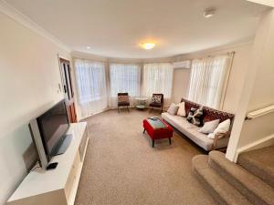 ein Wohnzimmer mit einem Sofa und einem TV in der Unterkunft 3 Bedroom Town house near Gosford CBD Sleeps 6 plus in Gosford