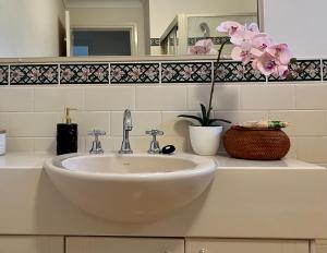 ein Badezimmer mit einem weißen Waschbecken und Blumen auf der Theke in der Unterkunft 3 Bedroom Town house near Gosford CBD Sleeps 6 plus in Gosford