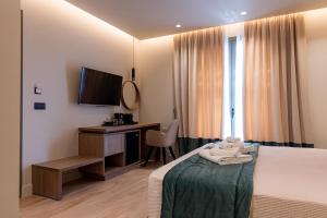 een slaapkamer met een bed, een bureau en een televisie bij Philia Boutique Hotel in Athene