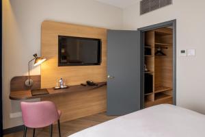 a bedroom with a desk and a tv on a wall at Gresham Belson Hotel Brussels in Brussels