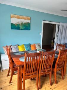 comedor con mesa, sillas y sofá en My Cottage On Main, en Boolaroo Racecourse