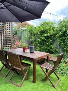 una mesa de madera con 2 sillas y una sombrilla en My Cottage On Main, en Boolaroo Racecourse