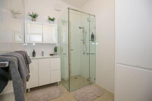 baño con ducha y puerta de cristal en My Cottage On Main, en Boolaroo Racecourse