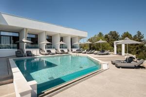 a swimming pool with chairs and umbrellas on a building at Akrotiri Olympus Luxury Suites - Adults Only in Plaka Litochorou