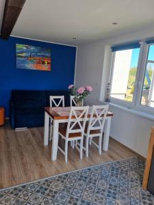 une salle à manger avec une table, des chaises et un mur bleu dans l'établissement Domki na Wzgórzu Jastrzębia Góra Tupadły, à Jastrzębia Góra