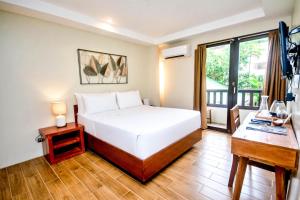 a bedroom with a bed and a desk and a window at Serene La Playa Boracay in Boracay