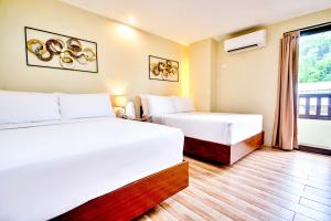 a hotel room with two beds and a window at Serene La Playa Boracay in Boracay