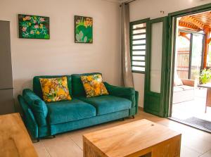 a living room with a green couch and a table at Villa Le Colonial Zen - T4 à 5 mn Aéroport in Sainte-Marie