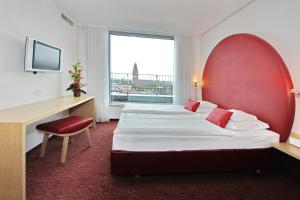 um quarto de hotel com duas camas e uma secretária e uma janela em ARCOTEL Rubin Hamburg em Hamburgo