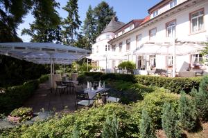 un giardino con tavoli e ombrelloni di fronte a un edificio di Hofgut Dippelshof Hotel- und Restaurant KG a Darmstadt