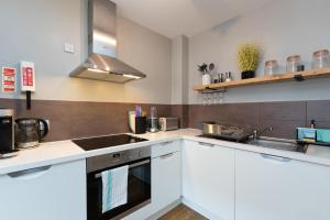 cocina con armarios blancos y fogones en High Street Town House, en Mánchester