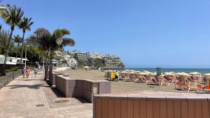 einen Strand mit Liegestühlen und Sonnenschirmen und dem Meer in der Unterkunft SAN AGUSTIN SEAVIEW BLUE APARTMENT in Maspalomas