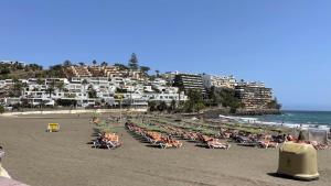 Ein Strand mit einem Haufen Stühle und Menschen darauf in der Unterkunft SAN AGUSTIN SEAVIEW BLUE APARTMENT in Maspalomas