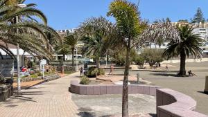 einen Park mit Palmen und Menschen auf dem Bürgersteig in der Unterkunft SAN AGUSTIN SEAVIEW BLUE APARTMENT in Maspalomas