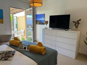 uma sala de estar com televisão e uma cama com toalhas amarelas em Tender Suite em Corralejo