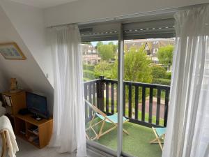 een kamer met een balkon en een glazen schuifdeur bij Picsine, Tennis résidence sévigné 300m mer in Deauville