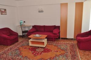 a living room with two red couches and a table at Hotel Lido in Mamaia