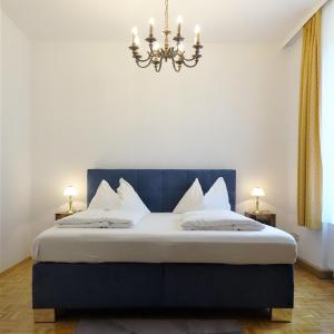 a bedroom with a bed with a blue headboard and a chandelier at Hotel Kindler 2,0 Self-Check-In in Leoben