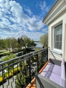 d'un balcon avec un banc et une vue sur l'eau. dans l'établissement Nowoczesny Apartament z widokiem na rzekę i jezioro, à Ełk