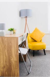 une chaise jaune assise à côté d'un bureau avec une lampe dans l'établissement Cedar Retreat, à Southampton