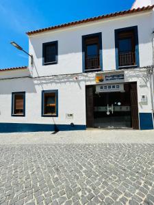 un edificio bianco con una porta e una strada di ciottoli di Só Mar a Vila Nova de Milfontes