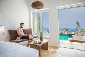 een man op een bank in een kamer met een raam bij KLIDON Dreamy Living Suites in Mykonos-stad