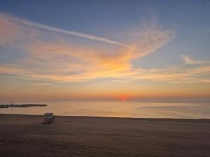 a bench sitting on the beach at sunset at Hotel H pe plaja Belona in Eforie Nord