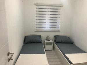 twee bedden in een kleine kamer met een raam bij Apartman M&D in Neum