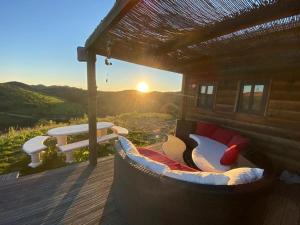 un sofá sentado en una terraza con la puesta de sol en el fondo en Portugals Infinity - Fantástica casa de campo com vista de mar em Tavira, en Tavira